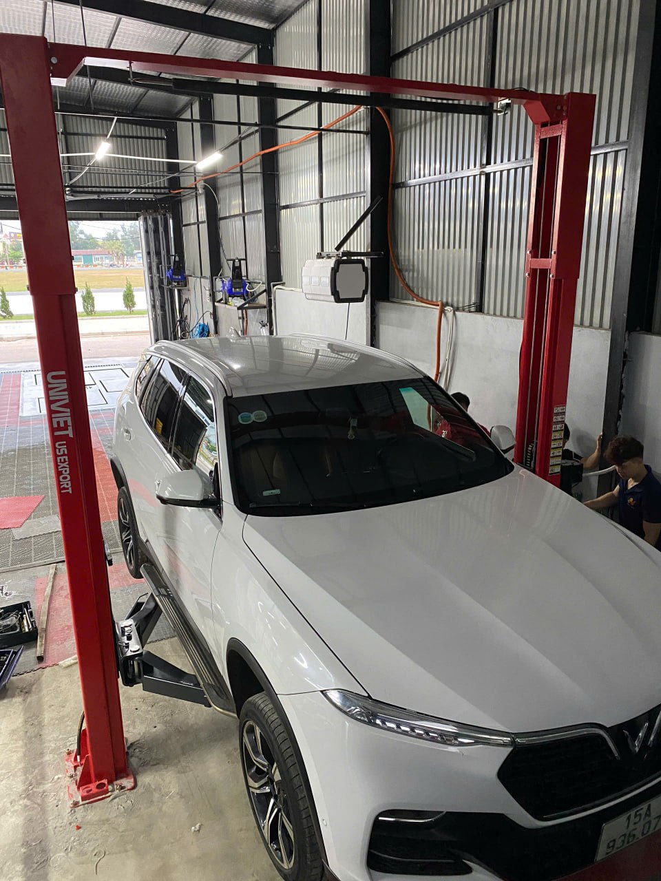 Xe VinFast Lux SA2.0 màu trắng trên cầu nâng 2 trụ màu đỏ trong gara